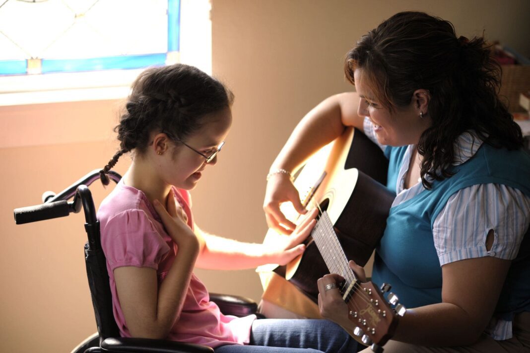 5d1237c3b41368276df4e17f_A girl with down syndrome listening to the guitar with Joyful Music Therapy-min senior woman holding chest because of chest pain