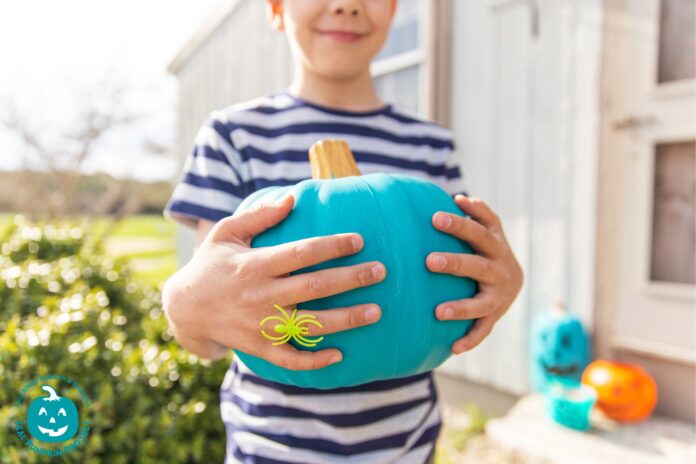 boy holding teal pumpkin. The teal pumpkin project helps create an inclusive Halloween experience.
