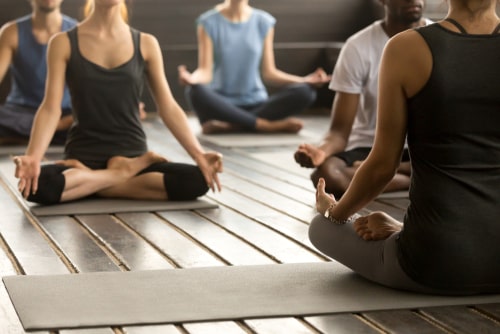 People in a seated yoga position during a class. Yoga is good for ADHD, autism, and many other disorders.