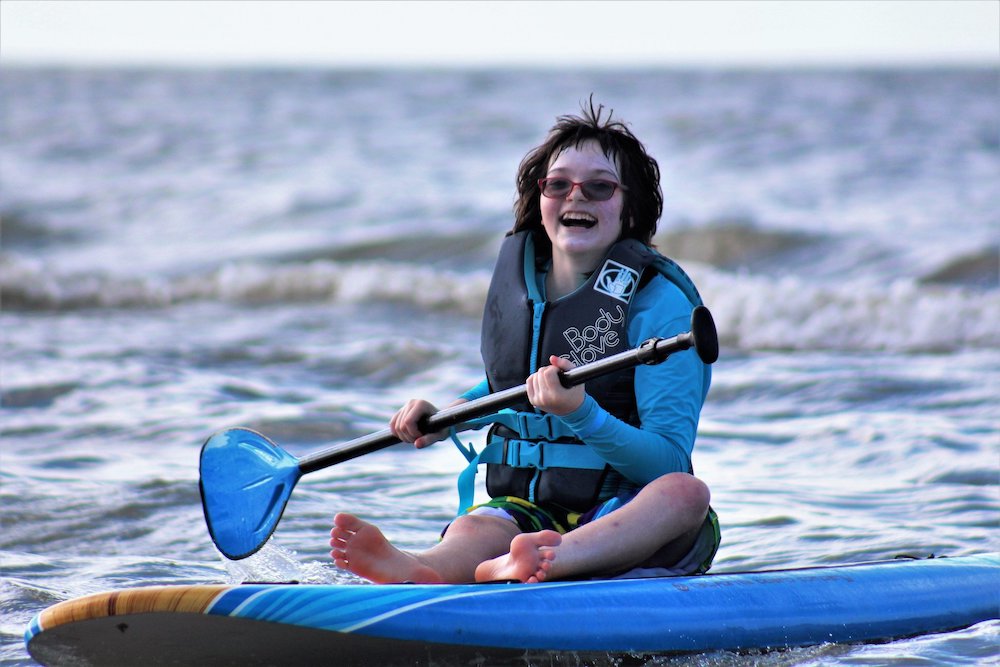 Girl on a paddleboard with surfers for autism