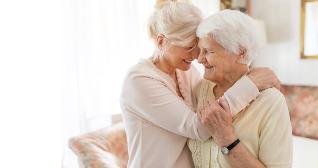 Senior aged women hugging senior age women hugging