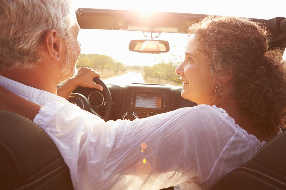 senior couple driving toward sunset