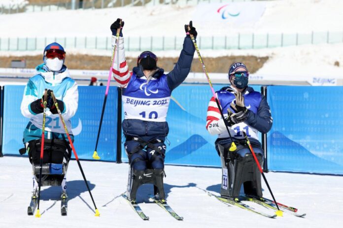 Oksana Masters of United States celebrates winning gold with silver medallist Yilin Shan of China and compatriot bronze medallist Kendall Gretsch in the women's Sprint Sitting Para Biathlon on Day One of the Beijing 2022 Paralympics Winter at Zhangjiakou National Biathlon Centre. ⒸLintao Zhang/Getty Images