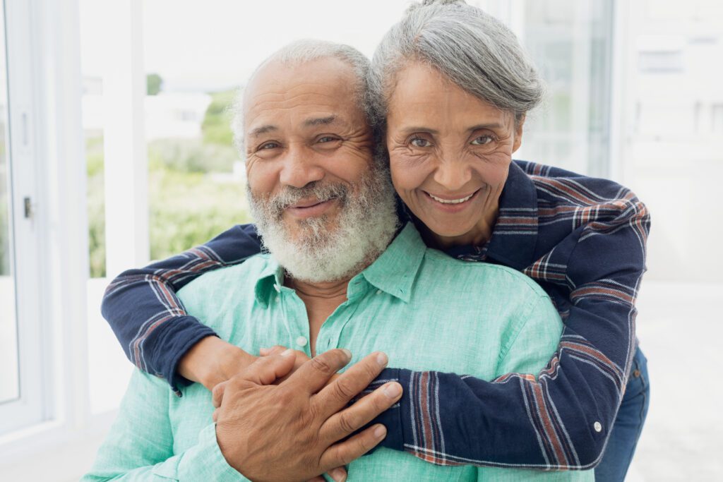 aging couple, woman wraps arms around man