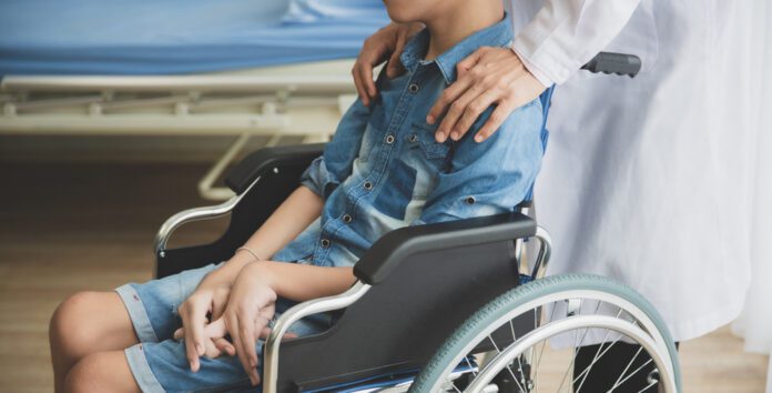 child seated in wheelchair being comforted by doctor