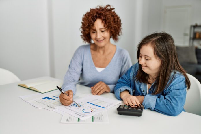 mother seated beside daughter with Down syndrome, working on taxes together