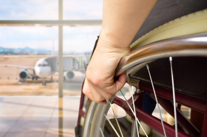 wheelchair using waiting in airport, overlooking airplane