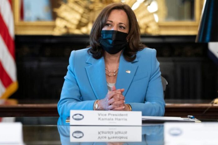 Vice President Kamala Harris, wearing a facial covering and blue suit, welcomes guest to a disability roundtable