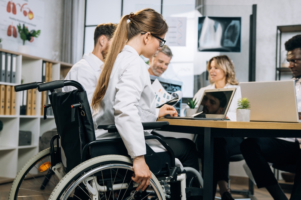 female doctor, in wheelchair, at table with fellow physicians