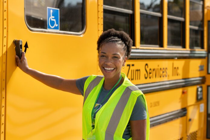 bus driver smiling and about to open handicapped accessible door on school bus