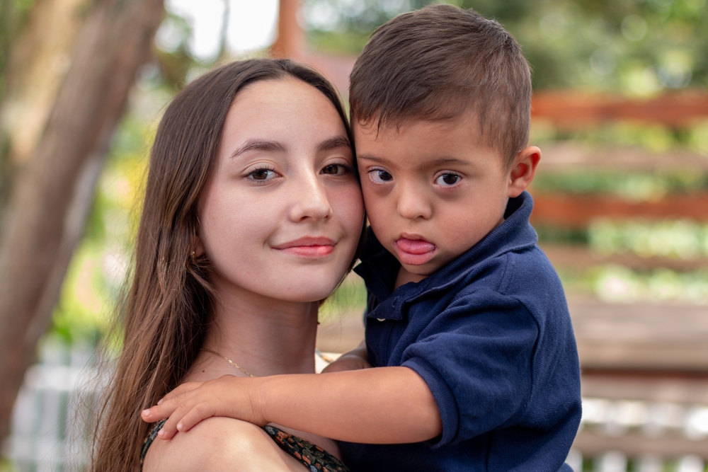 Hispanic girl holding a Hispanic boy with down syndrome, Latinx disabilities