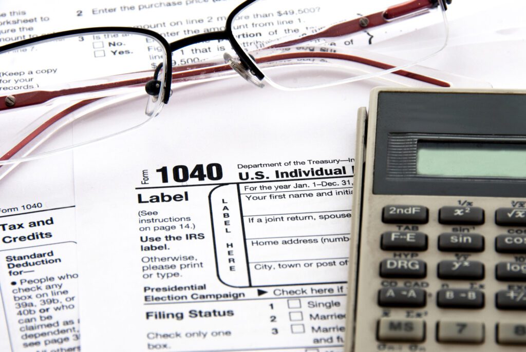 Calculating individual refund taxes and filling out the US 1040 Tax Form - form, calculator, glasses