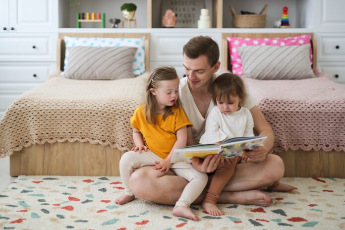 March is National Reading Month. A dad reads disability books to his two kids, one of which has Down syndrome.