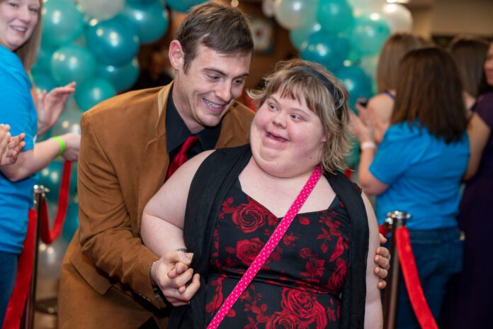 Aurora, CO / USA - February 7 2020: A man and a woman with special needs walk down a red carpet at the Tim Tebow Foundation Night To Shine Prom at Peace with Christ Church