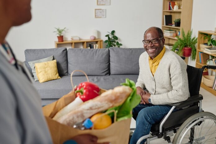 man, smiling and in wheelchair, receives food access via home delivery