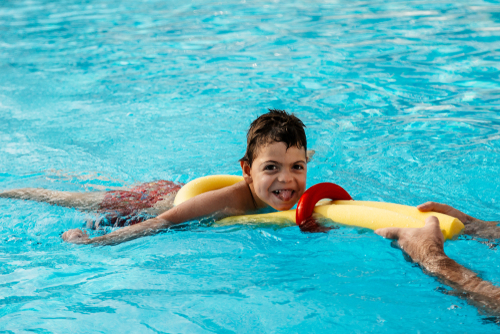 Boy, with special needs, using a pool floatation device. 