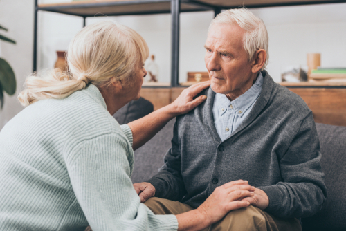 Senior couple with hands gently placed on each other in support, discuss resources for Alzheimer’s