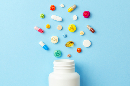 Bottle of vitamins, which may help improve brain health, with varying pills coming out of top. 