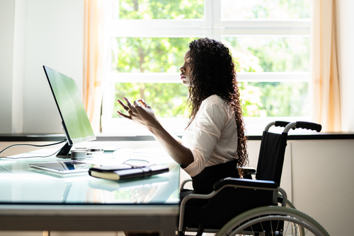 Women, a wheelchair user, meditates at her desk.