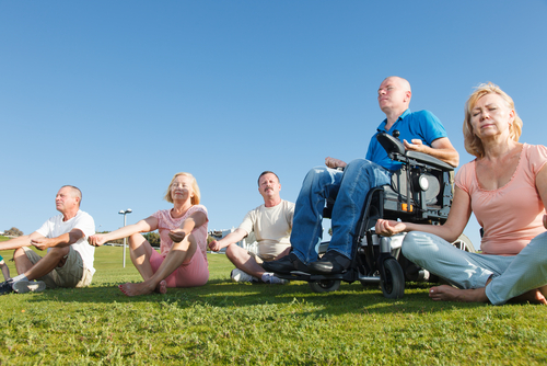 Senior aged people, including man in motorized wheelchair, meditate.
