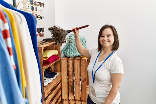 A woman, who has Down syndrome, dusts off a shelf. 