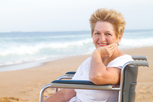 An aging woman in a wheelchair on the beach. | All people should learn sunscreen tips for people with disabilities. 