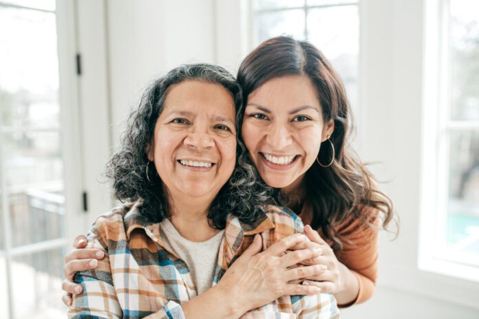 A Spanish-speaking caregiver and her mother smiling.