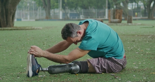 man with leg prosthetic stretching