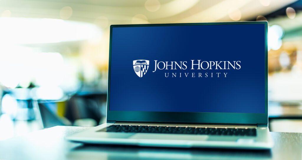 Open laptop on desk with logo of Johns Hopkins University on the screen.