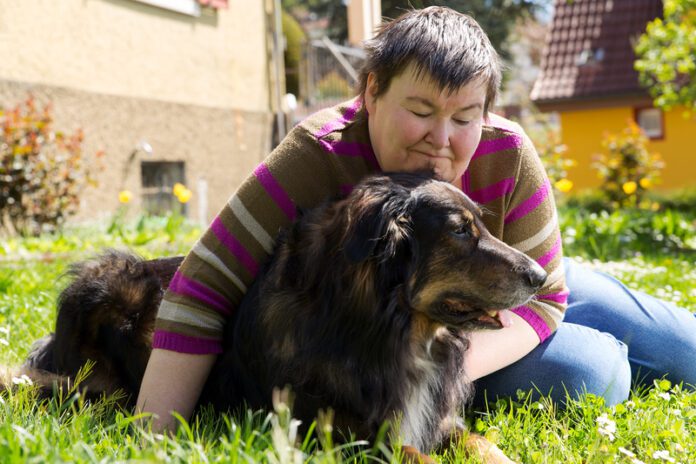 Mentally disabled woman is lying with dog on a lawn