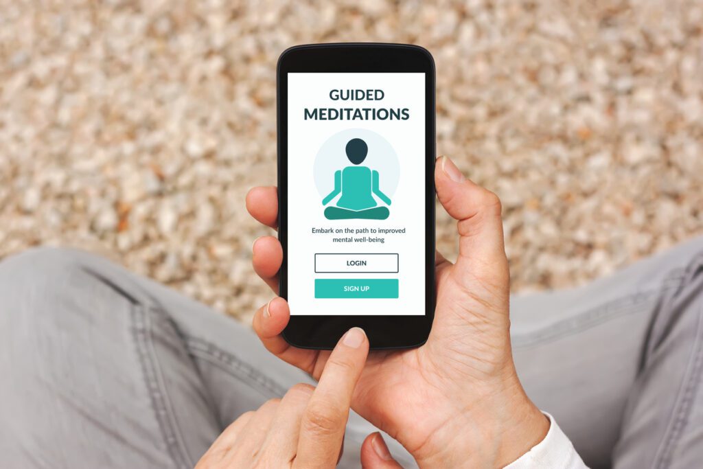 Hands holding smartphone with meditation app concept on screen. Flat lay