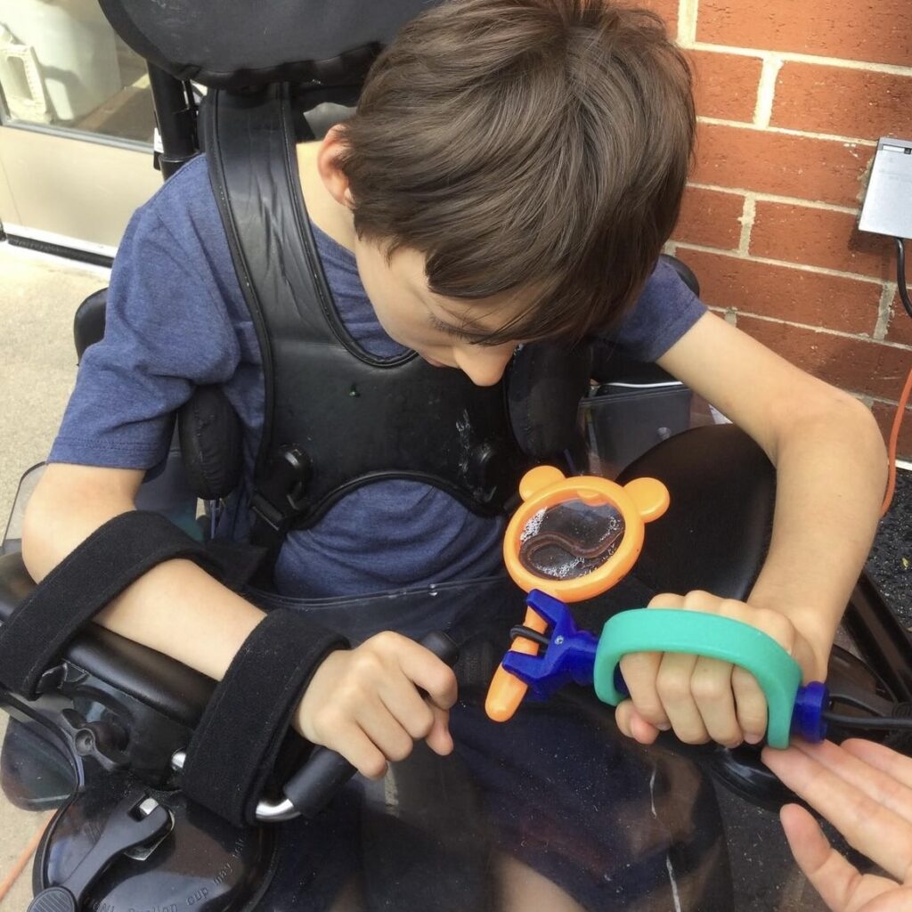 Child with disability using an EasZyHold cuff to hold a magnifying glass