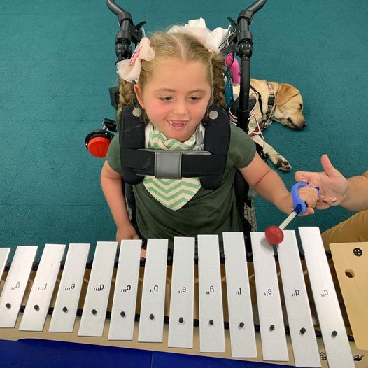 Young girl with disability playing a xylophone using the EaZyHold cuff