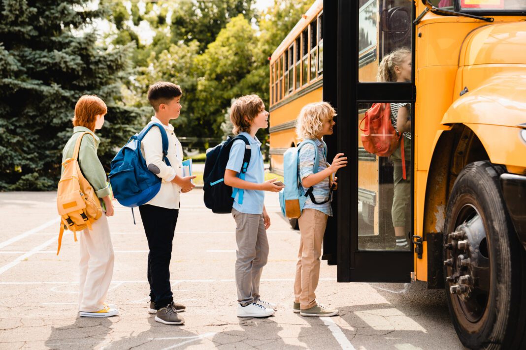 Multiethnic mixed-race students standing in line boarding the school bus
