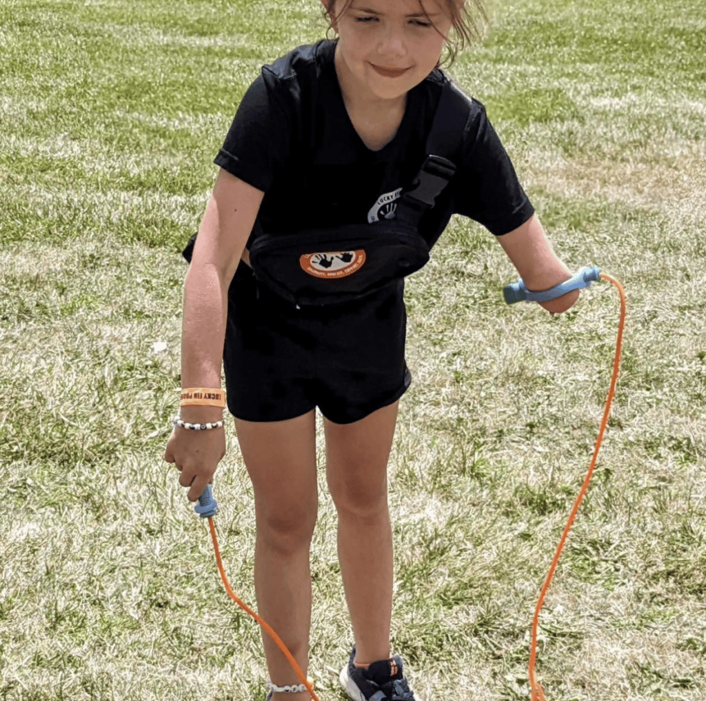 Child with limb difference jump roping using EaZyhold cuffs to grip the jump rope handles