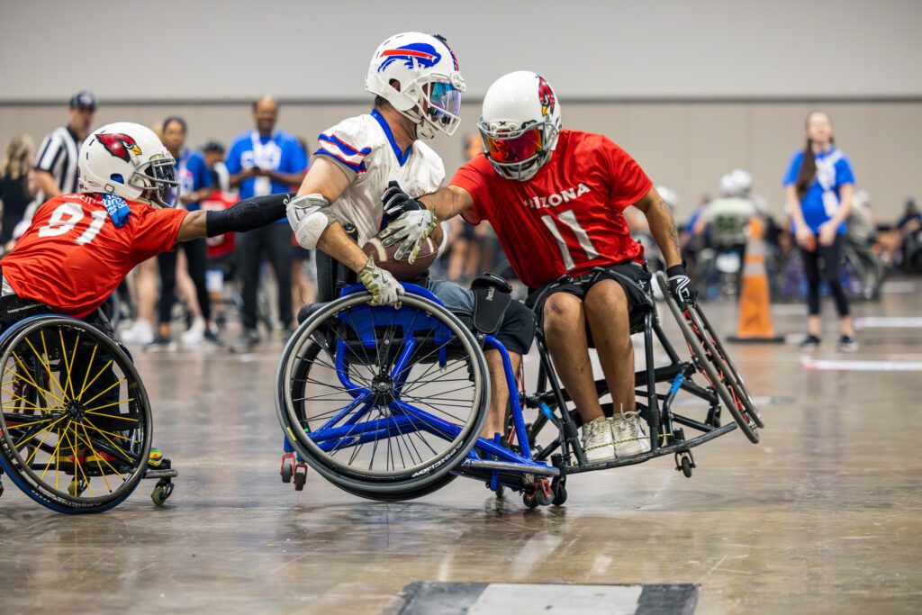 Adapted football players intercepting player with football.