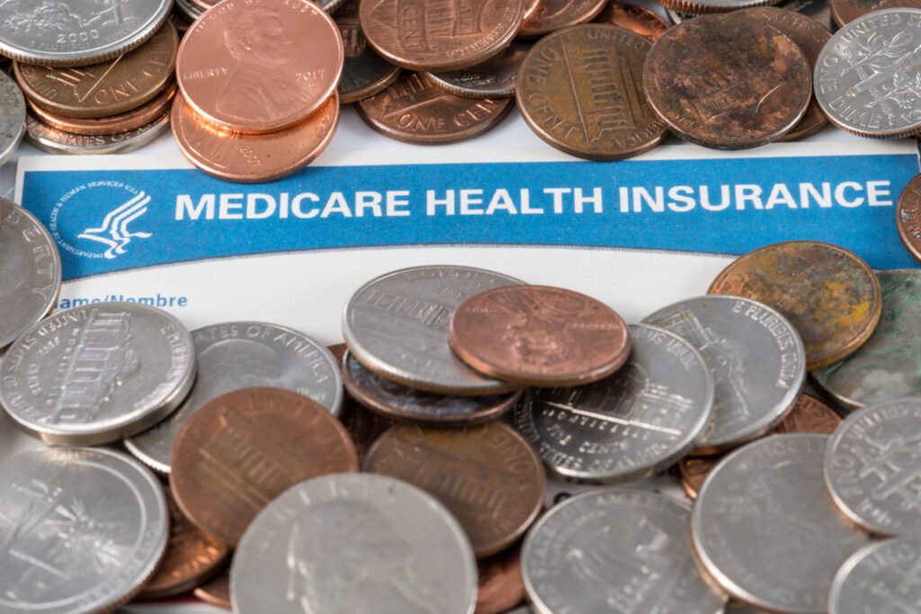 USA Medicare health insurance card with piles of loose change and cash to show funding crisis