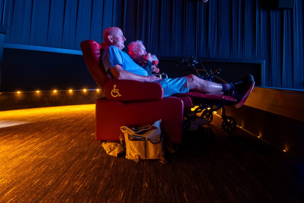 Lexington Park, Maryland USA A man sits in a reclining handicapped seat in a movie theatre during the projection of a movie.