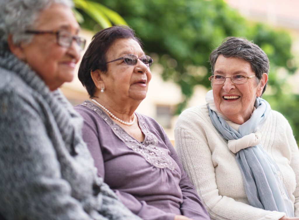 Happy elderly women sitting on bench in park smiling best friends enjoying retirement together