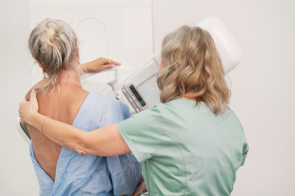 50-year-old woman undergoes mammography procedure on special medical equipment mammograph with the help of assistant in modern clinic. Regular medical examination, screening for breast cancer