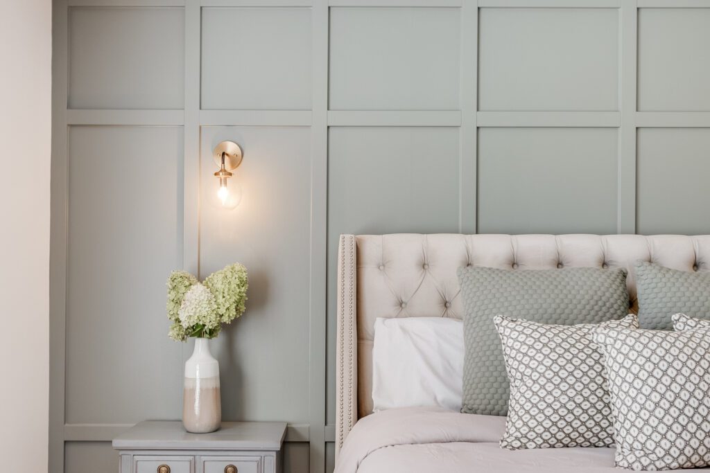 A modern design bedroom with textured wall behind the bed and cozy green tones throughout